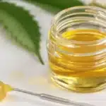 Fresh butane hash oil in a glass container with a dab tool nearby