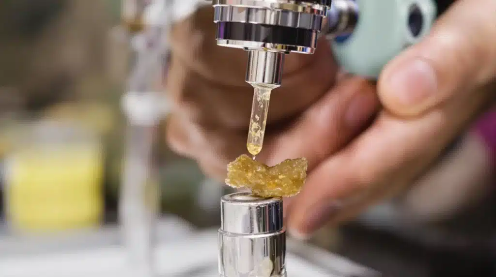 Hand holding a dab tool with live resin being placed onto a heated nail of a dab rig