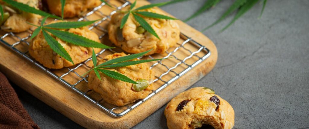 Freshly baked cannabis cookies cooling on a rack, garnished with cannabis leaves.