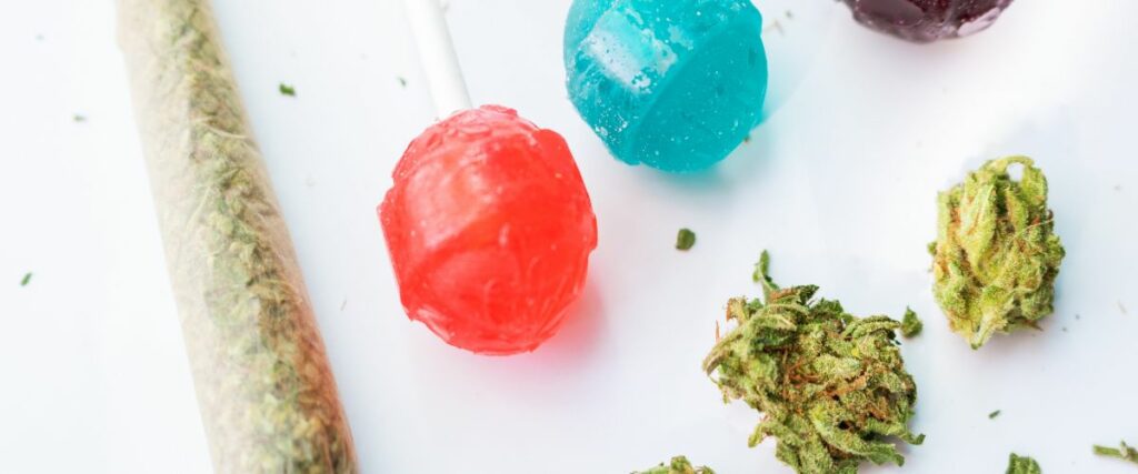Colorful THC-infused lollipops and a cannabis joint with cannabis buds.