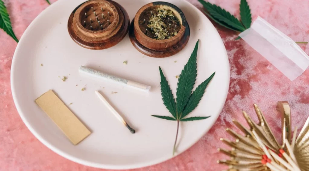 Plate with a cannabis joint, grinder, and leaf, illustrating the preparation process using medical marijuana seeds for therapeutic purposes.