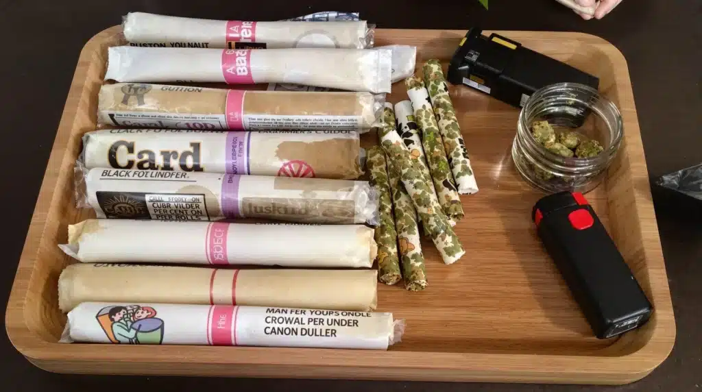 Pre-rolls displayed on a wooden tray with tools nearby, illustrating the setup for how to light pre rolled weed effectively