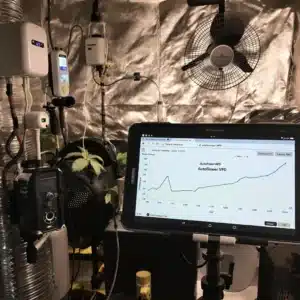 High-tech cannabis grow room with autoflower VPD chart monitoring on a tablet.