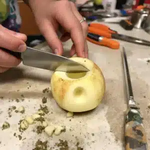 Crafting an apple pipe for smoking cannabis using a knife, with household items on a kitchen counter.