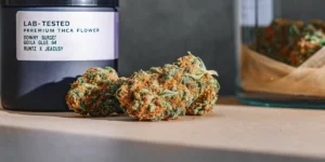Hyper-realistic close-up of "LAB TESTED PREMIUM THCA FLOWER" buds with orange pistils next to a labeled black container and a glass jar.