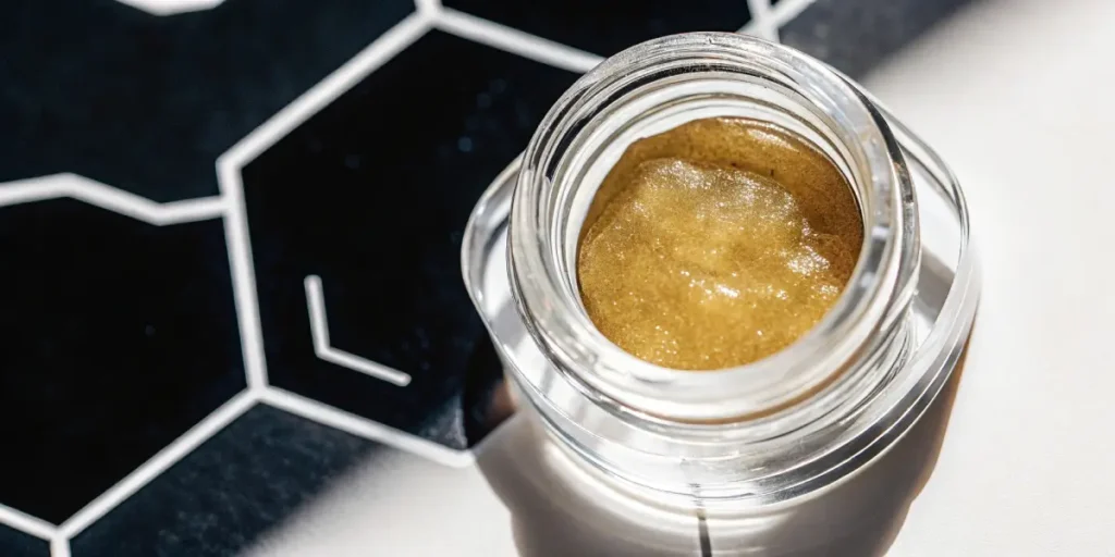 Premium cannabis live resin in glass jar with cannabis leaf background