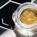 Premium cannabis live resin in glass jar with cannabis leaf background