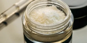 THCA isolate in a transparent jar with lab tools in the background.