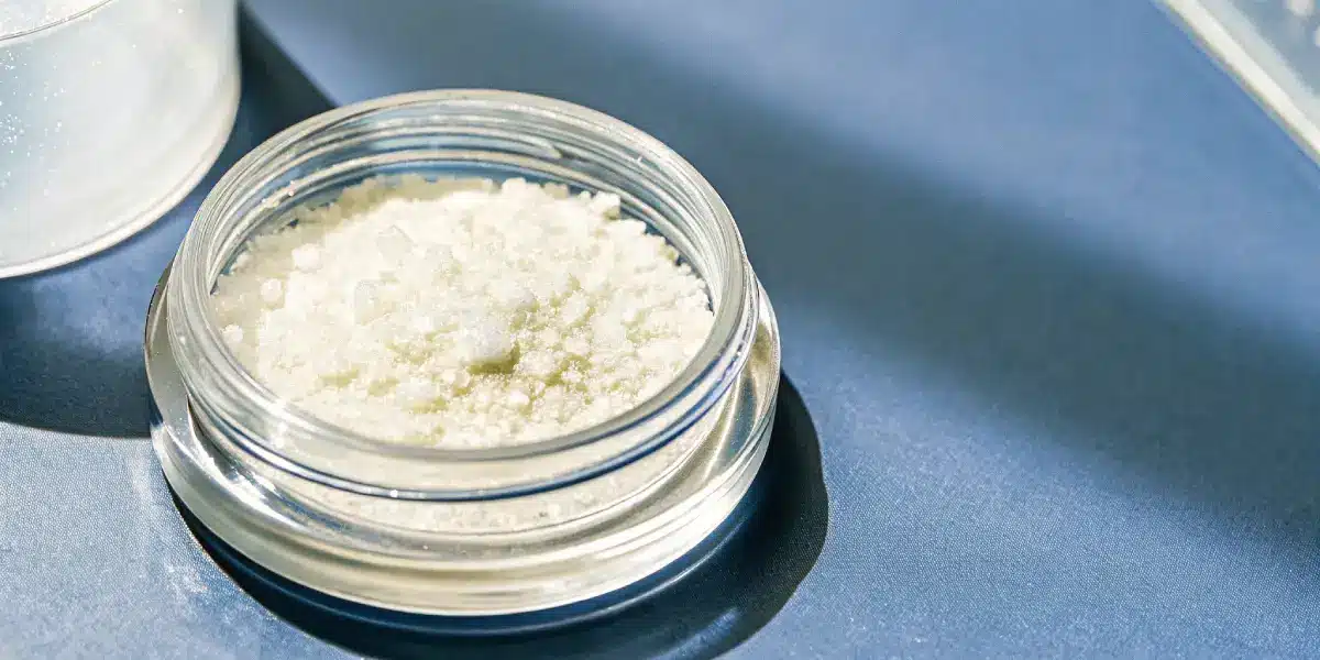 Close-up of THCA isolate crystals in a jar under natural sunlight.