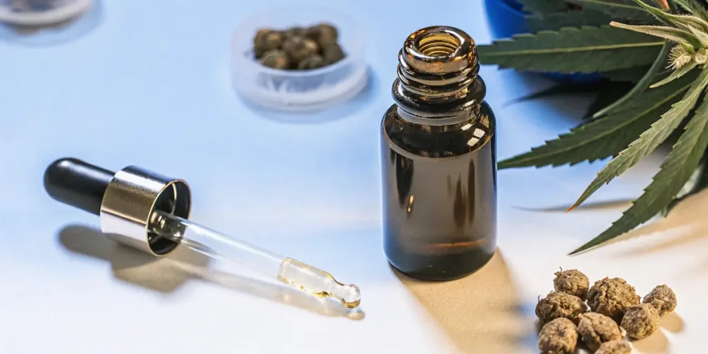 full extract cannabis oil dropper and amber glass bottle with cannabis seeds and leaves