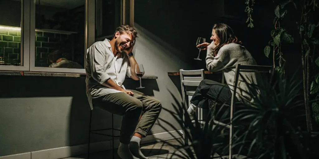 Man and woman enjoying wine and conversation on a dark patio at night.
