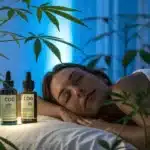 Woman sleeping peacefully on a massage table surrounded by cannabis plants, with CBD bottles softly illuminated under a calming blue light