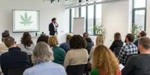 Experts leading a seminar on cannabis treatment for autism in a conference room, with attentive participants.