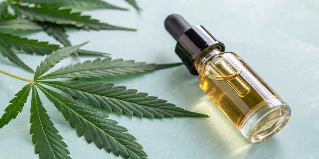 A row of amber dropper bottles with blank labels on a well-lit store shelf, with blurred cannabis leaf designs below.