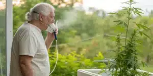 COPD patient using a portable oxygen device near a cannabis plant, illustrating natural support for breathing.