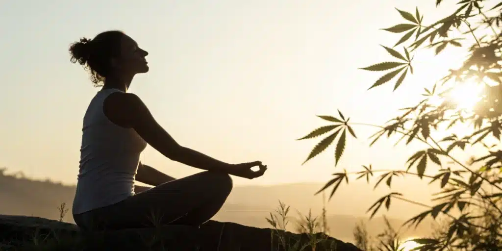 Person meditating outdoors with cannabis leaves, representing natural relief for fibromyalgia.