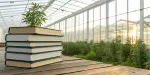 Realistic image showing best cannabis growing books displayed on a table with a greenhouse backdrop.