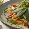 A colorful salad featuring fresh cannabis leaves, vegetables, and dressing highlighting Can You Eat Cannabis Leaves? Benefits and Preparation Tips