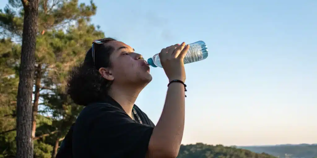 Realistic scene of a person drinking water after cannabis consumption, illustrating the immediate need to counteract dry mouth.