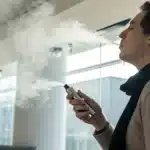 Realistic image of an individual using a vaporizer for natural relief, demonstrating how weed can help with sore throat symptoms.