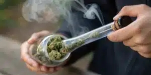 Realistic image illustrating the steamrolling technique with a glass pipe filled with cannabis and concentrated smoke.