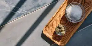 Overhead shot: rustic wooden tray with a small bowl of cannabis and a larger bowl of salt.