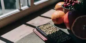 Tray of cannabis seeds with citrus fruits and berries by a window.