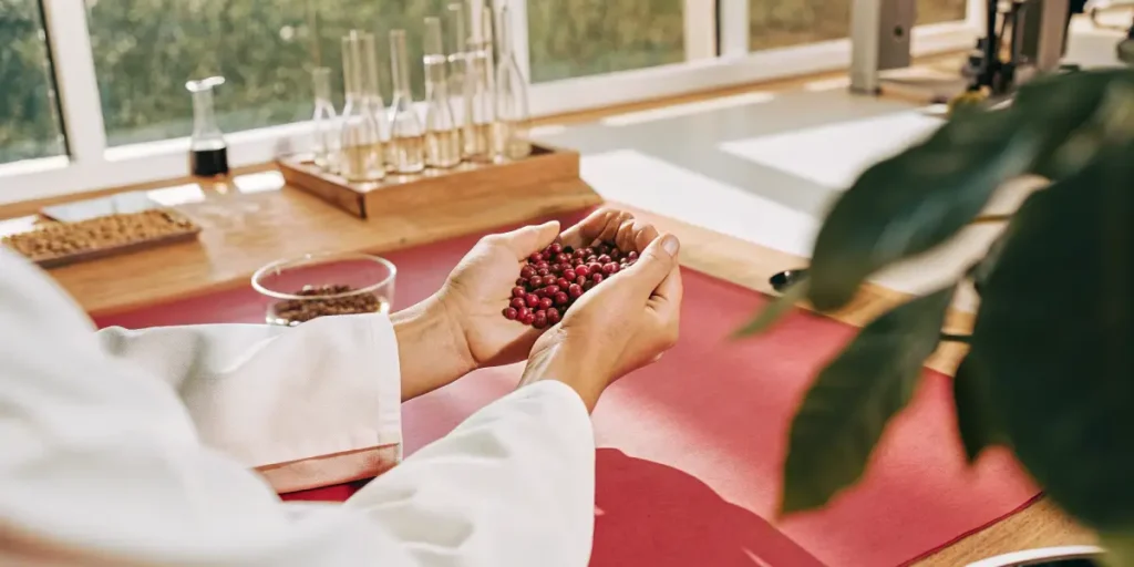 A scientist in a lab coat holding a handful of red berries.