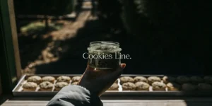 Hand holding a jar labeled Cookies Line with cannabis seeds outdoors.